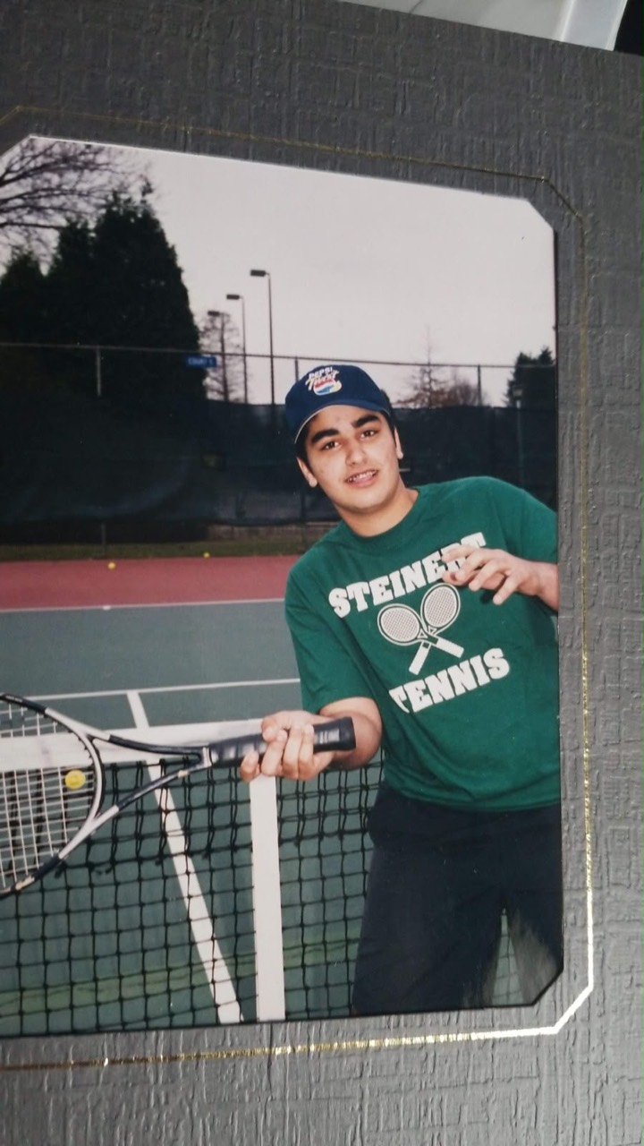 Usman standing at a tennis net with a racket